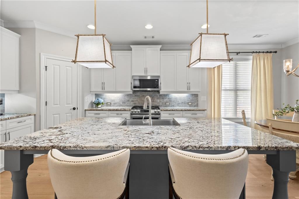 4469 Tacoma Trace Suwanee, GA 30024 - Photo 7 of 62 a kitchen with a sink a stove and chairs
