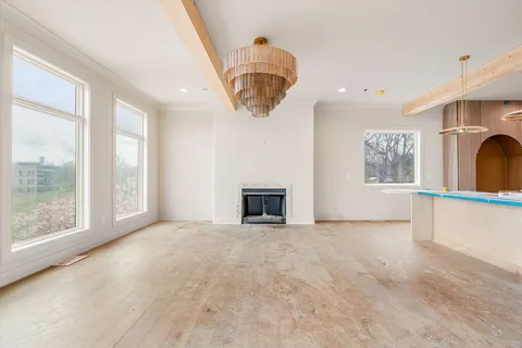 a view of an empty room with a window and a kitchen area
