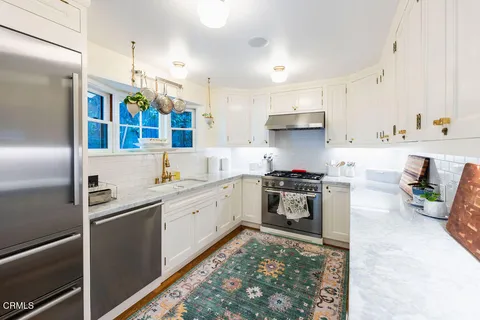 a kitchen with stainless steel appliances granite countertop a refrigerator a stove and a sink with wooden floor