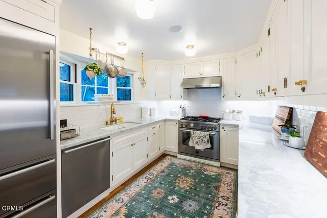 a kitchen with stainless steel appliances granite countertop a refrigerator a stove and a sink with wooden floor