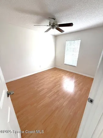 an empty room with wooden floor a ceiling fan and windows