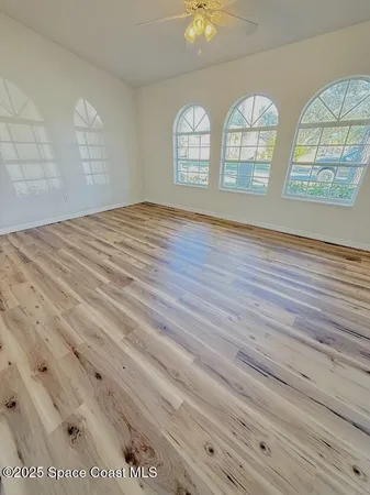 an empty room with wooden floor and windows
