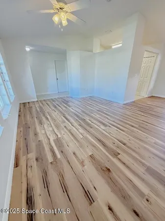 a view of a room with wooden floor and ceiling fan
