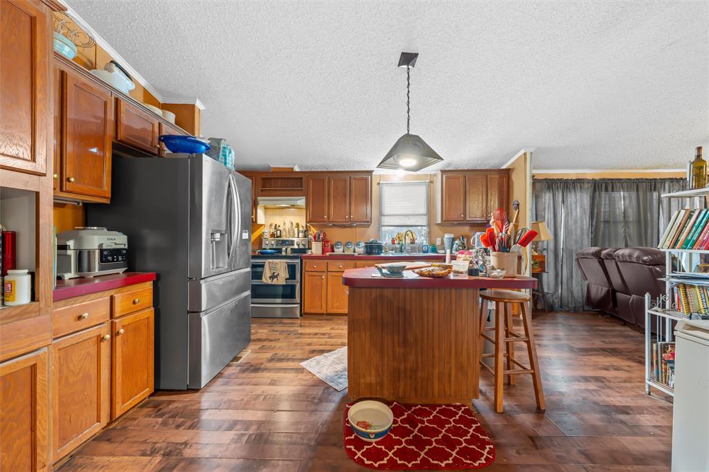 236 Bode Road Elm Mott, TX 76640 - Photo 12 of 33 a kitchen with stainless steel appliances granite countertop a refrigerator a sink dishwasher a dining table and chairs with wooden floor