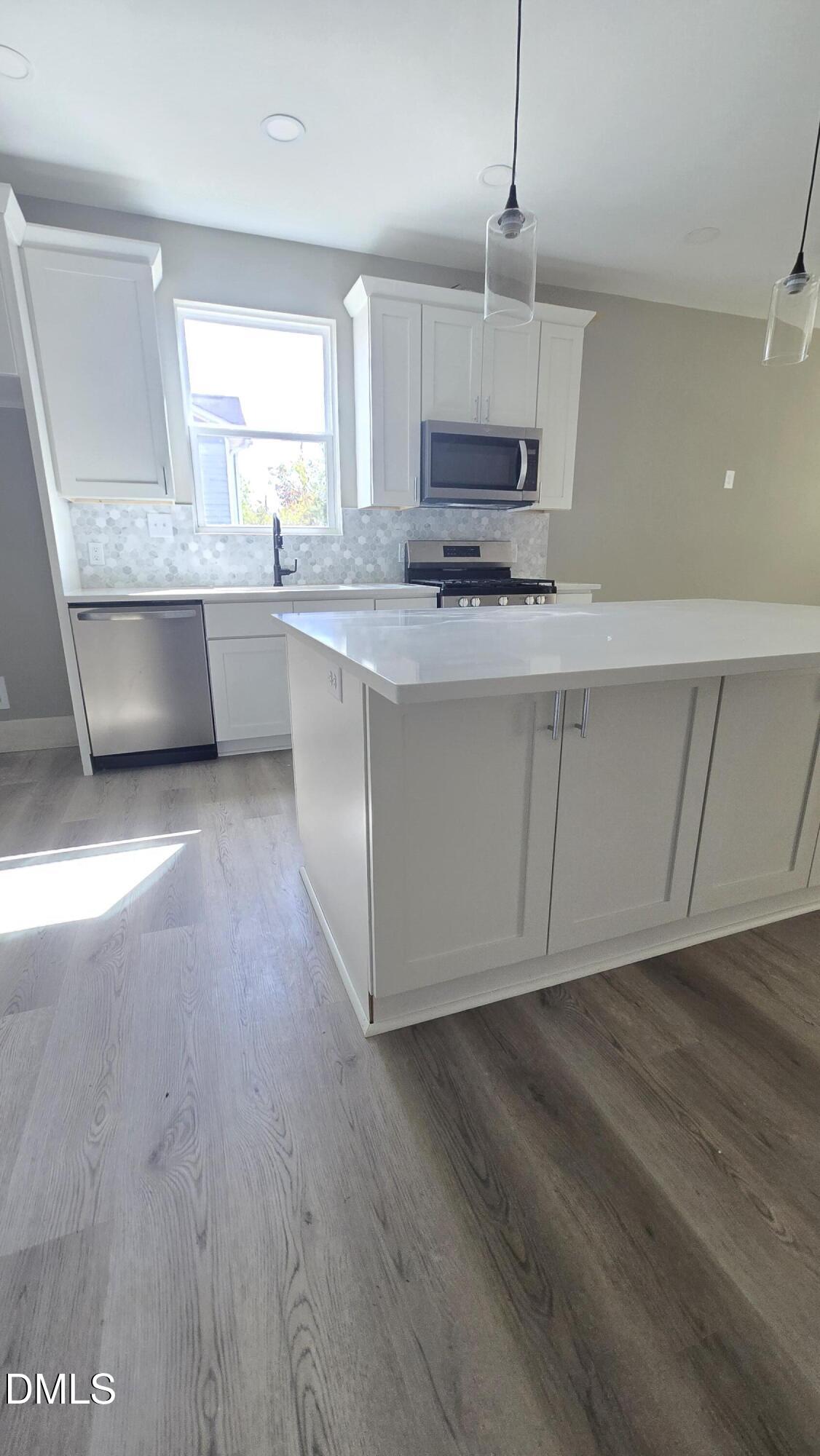 1013 Carroll Street, Unit B Durham, NC 27707 - Photo 3 of 4 a kitchen with stainless steel appliances granite countertop a sink a stove a microwave a refrigerator a white cabinets and wooden floor