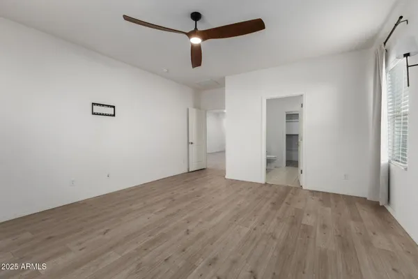 an empty room with wooden floor and ceiling fan