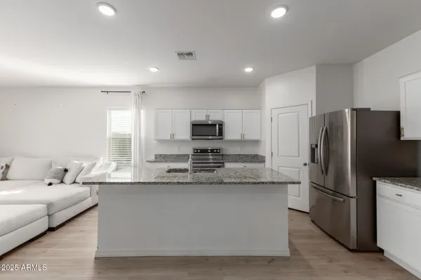 a large kitchen with granite countertop a large counter top stainless steel appliances and cabinets