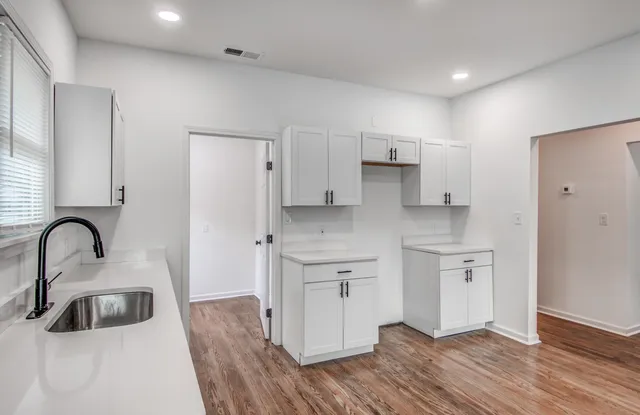 a kitchen with a sink cabinets and wooden floor