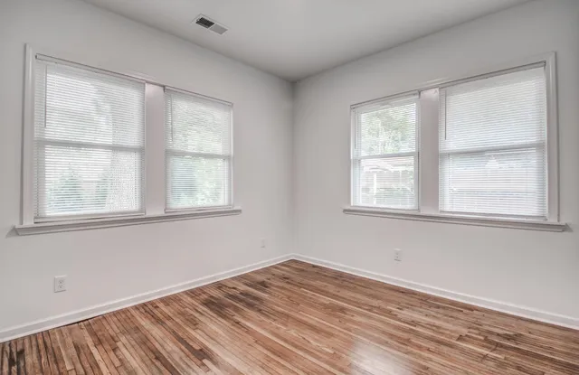 a view of empty room with wooden floor and fan