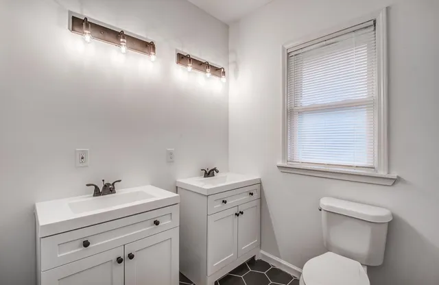 a bathroom with a sink toilet vanity and window