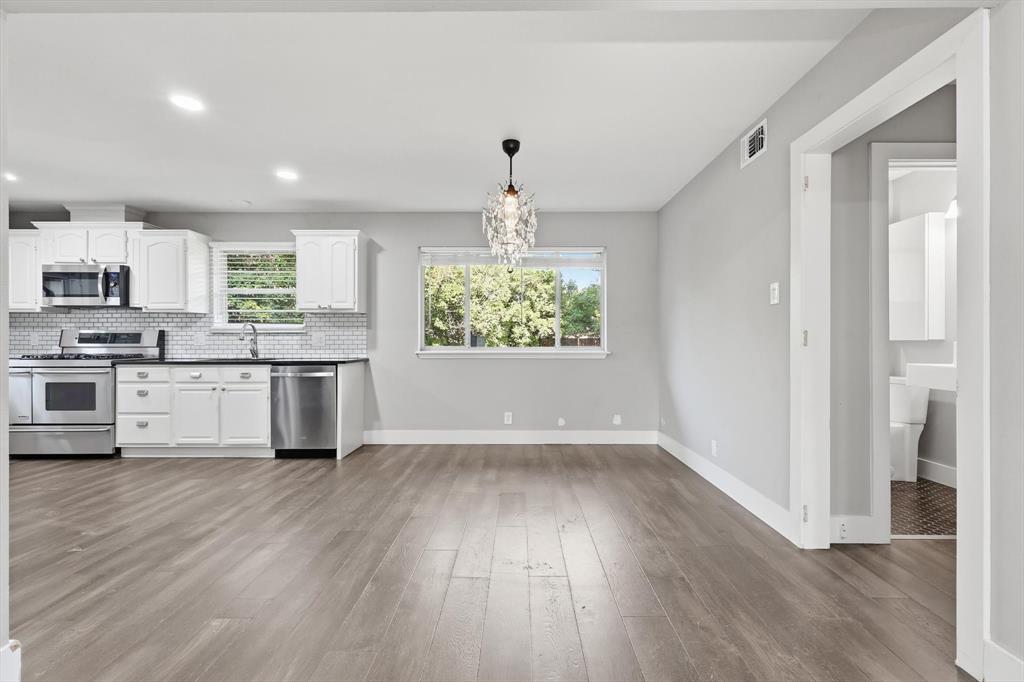 6611 Highgate Lane Dallas, TX 75214 - Photo 12 of 39 Kitchen with dark wood-type flooring, stainless steel appliances, hanging light fixtures, white cabinetry, and backsplash