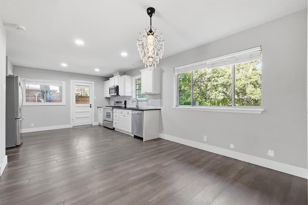 6611 Highgate Lane Dallas, TX 75214 - Photo 13 of 39 Kitchen with white cabinets, tasteful backsplash, stainless steel appliances, dark wood finished floors, and a chandelier