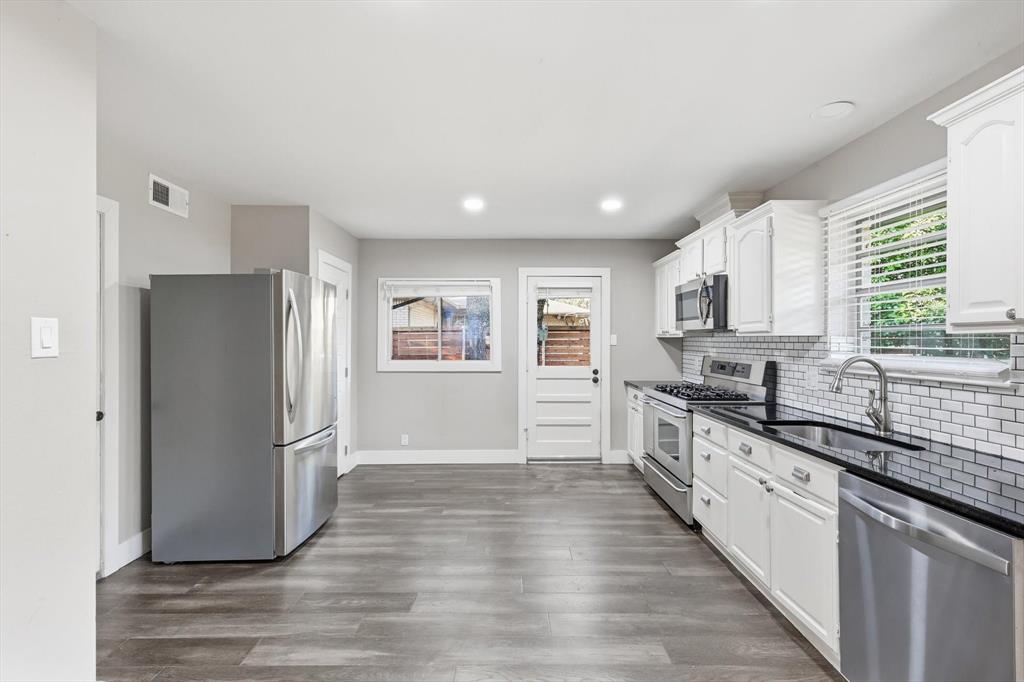 6611 Highgate Lane Dallas, TX 75214 - Photo 20 of 39 Kitchen with appliances with stainless steel finishes, white cabinets, dark wood-style floors, tasteful backsplash, and recessed lighting