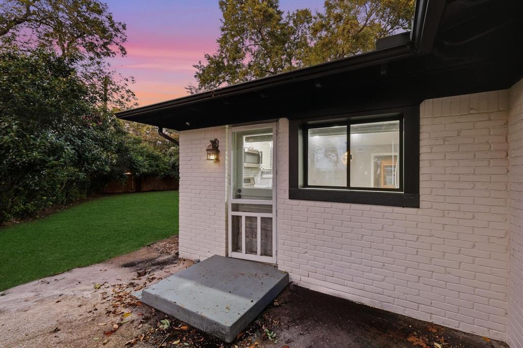 6611 Highgate Lane Dallas, TX 75214 - Photo 34 of 39 Exterior entry at dusk featuring brick siding and a patio