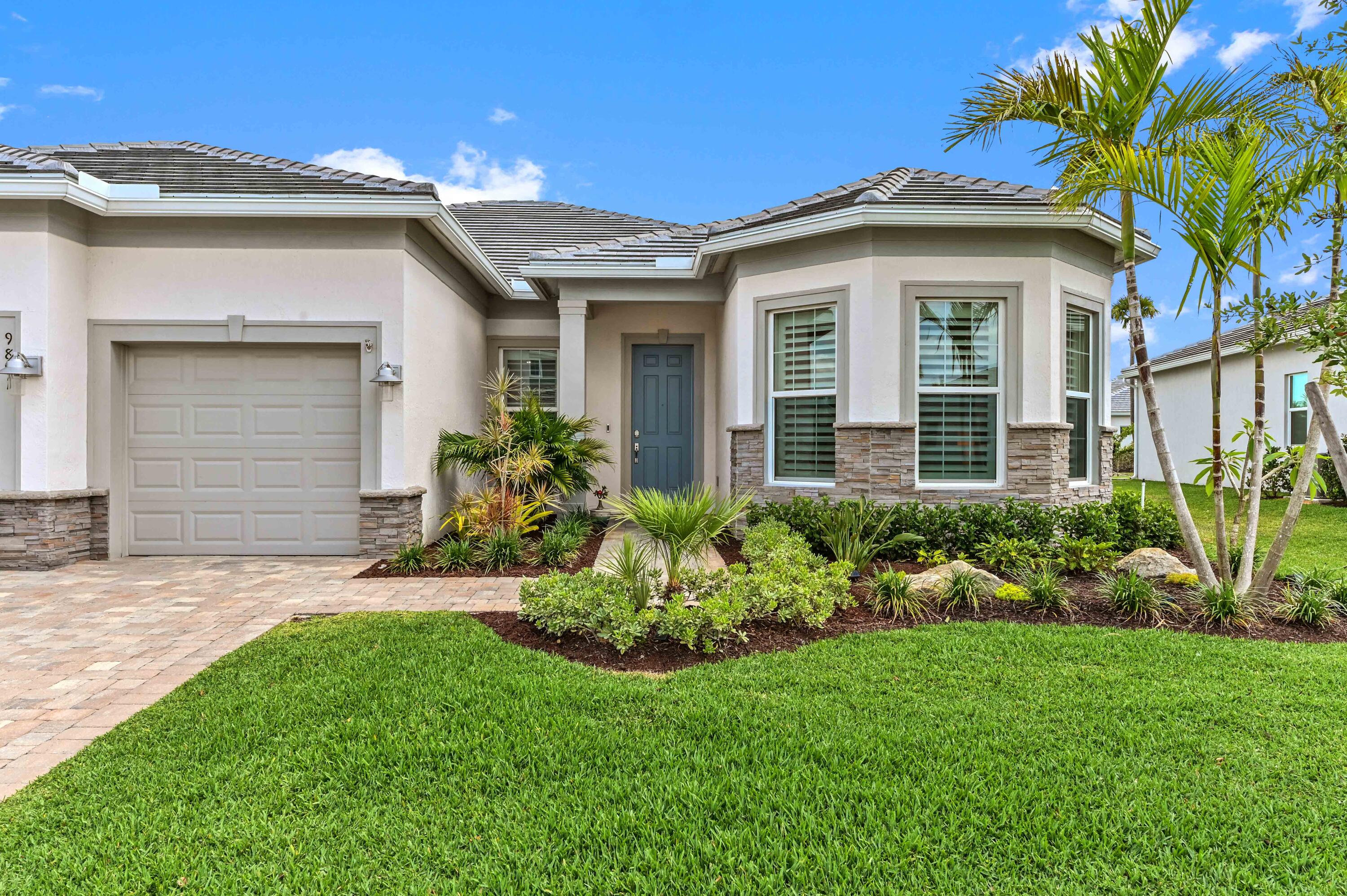 9891 Southwest Legacy Drive Stuart, FL 34997 - Photo 2 of 55 a front view of a house with a garden and plants