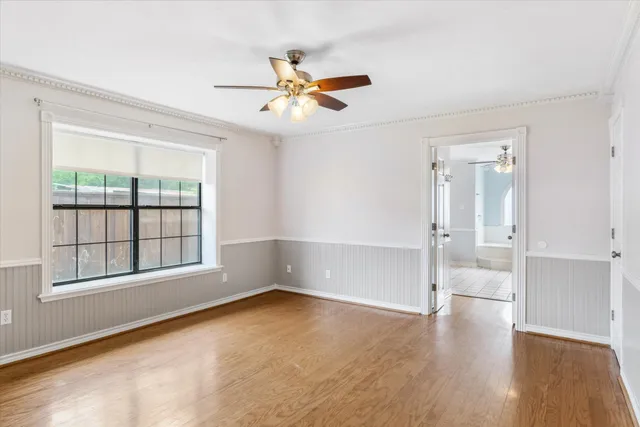 a view of empty room with wooden floor and fan