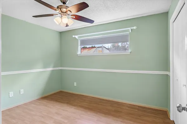 an empty room with wooden floor and fan