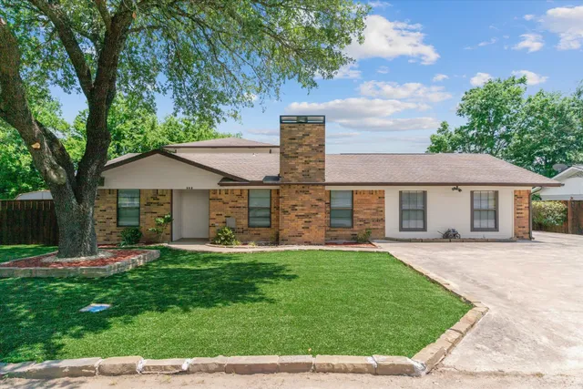 a front view of a house with a yard and trees