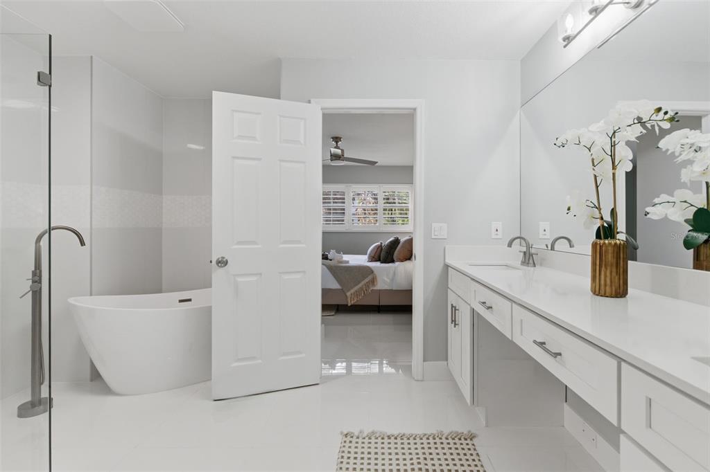 8044 Sandpoint Boulevard Orlando, FL 32819 - Photo 28 of 34 a en suite bathroom with a double vanity sink a mirror and a bathtub