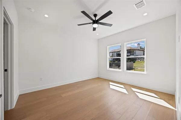 an empty room with windows and ceiling fan