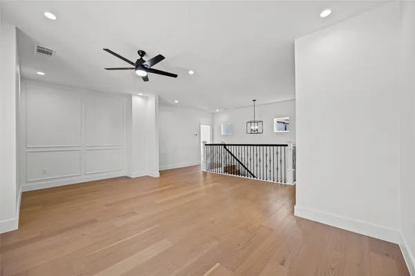 a view of an empty room with wooden floor and windows
