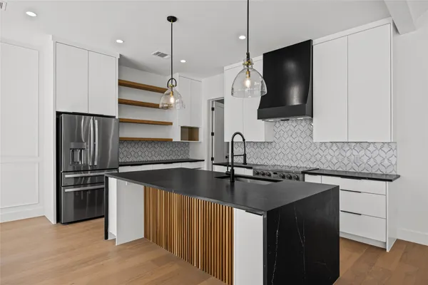 a kitchen with stainless steel appliances granite countertop a sink a microwave a refrigerator and a stove