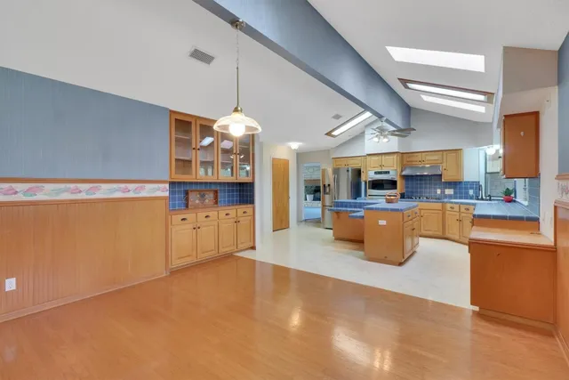 a kitchen with stainless steel appliances granite countertop wooden cabinets a stove a sink and a large window