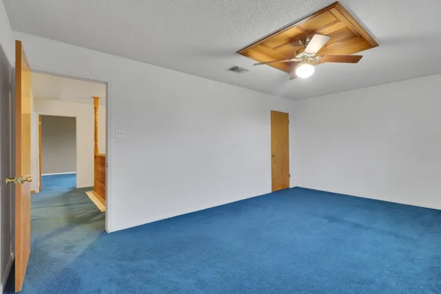 an empty room with windows and chandelier fan