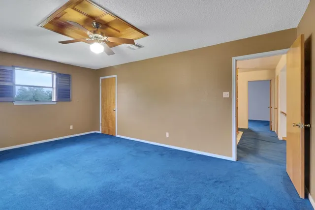 an empty room with windows and ceiling fan