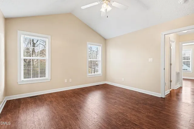 a view of an empty room with wooden floor and a window