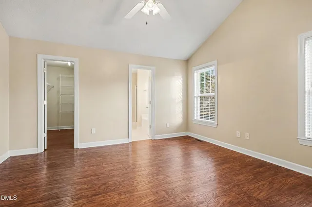 an empty room with wooden floor chandelier fan and window
