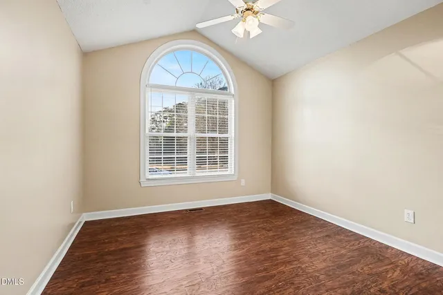 a view of an empty room with a chandelier fan