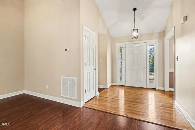 an empty room with wooden floor a ceiling fan and fireplace