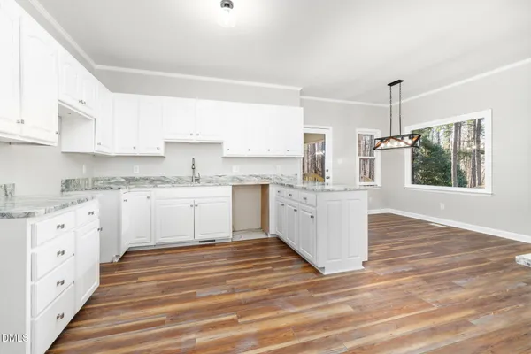 a view of an empty room with wooden floor and a fireplace