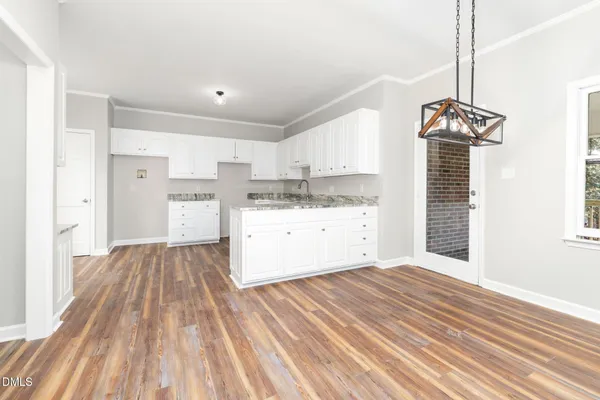 a large white kitchen with cabinets and wooden floor