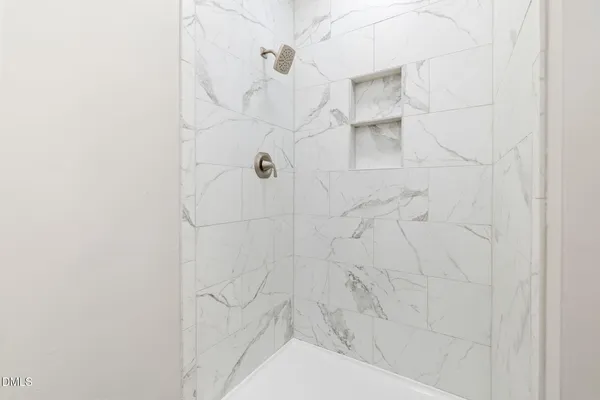 a view of an empty room with wooden floor and a ceiling fan