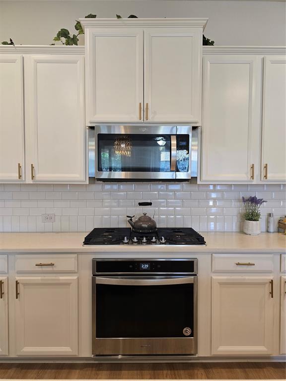 7024 Tree Stand Point Little Elm, TX 76227 - Photo 8 of 30 a kitchen with stainless steel appliances granite countertop a stove a microwave and cabinets