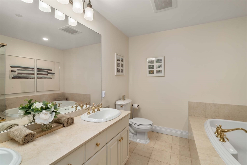 630 Hammond Street, Unit 102 Brookline, MA 02467 - Photo 14 of 19 a bathroom with a granite countertop sink a toilet and a mirror