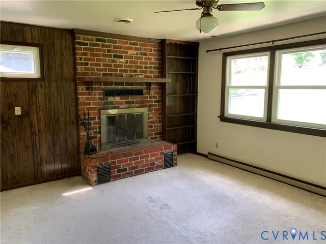 an empty room with windows and fireplace