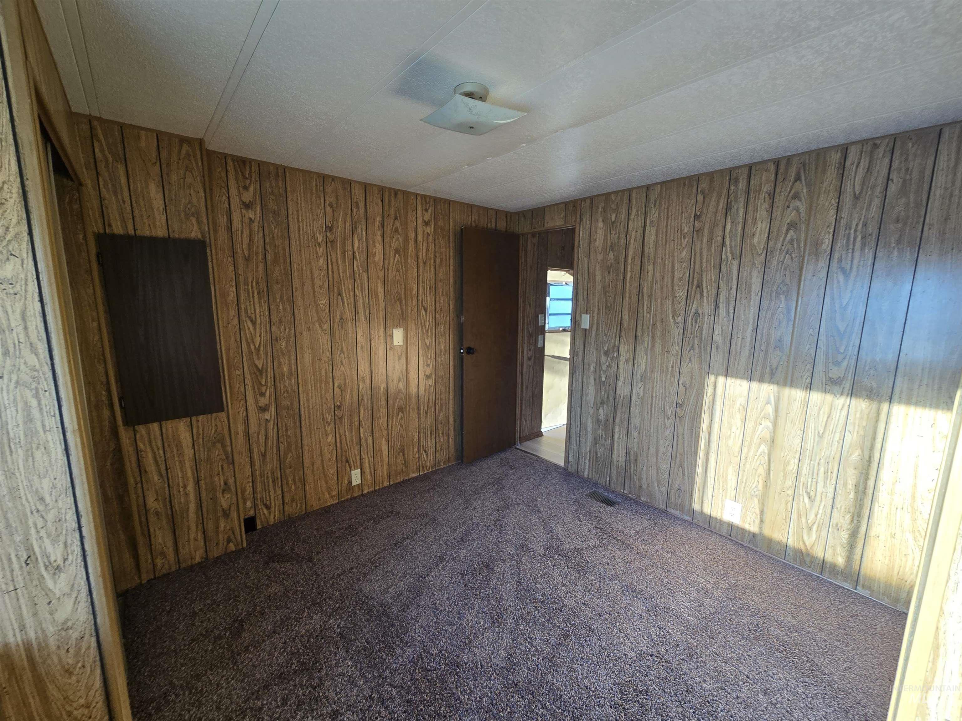 198 South Hills Road, Unit 148 Twin Falls, ID 83301 - Photo 11 of 18 Wood-paneled walls with contrasting wood trim, wall-to-wall carpeting, and a flush-mount ceiling light