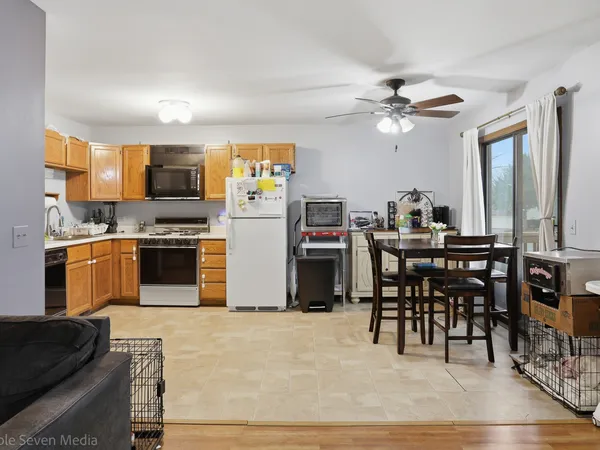 a kitchen with stainless steel appliances kitchen island granite countertop a table chairs sink and cabinets