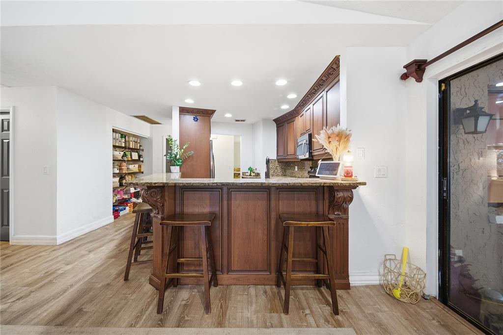 4602 Buckeye Road Tampa, FL 33624 - Photo 17 of 36 a kitchen with stainless steel appliances granite countertop a refrigerator a stove top oven a dining table and chairs with wooden floor