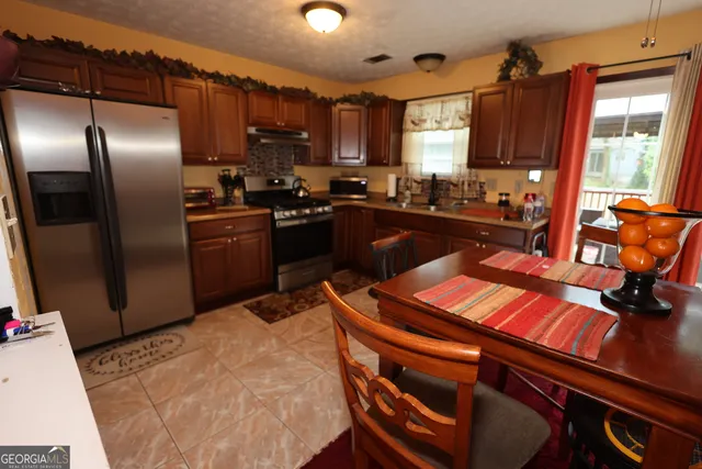 a kitchen with stainless steel appliances granite countertop a refrigerator a stove top oven a sink and dishwasher