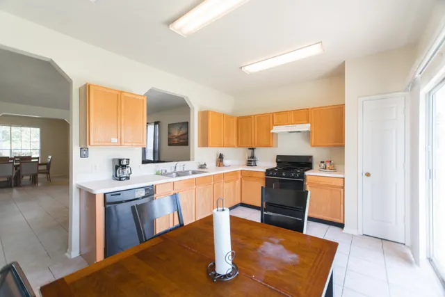 a kitchen with stainless steel appliances granite countertop a stove top oven a sink a dining table and chairs