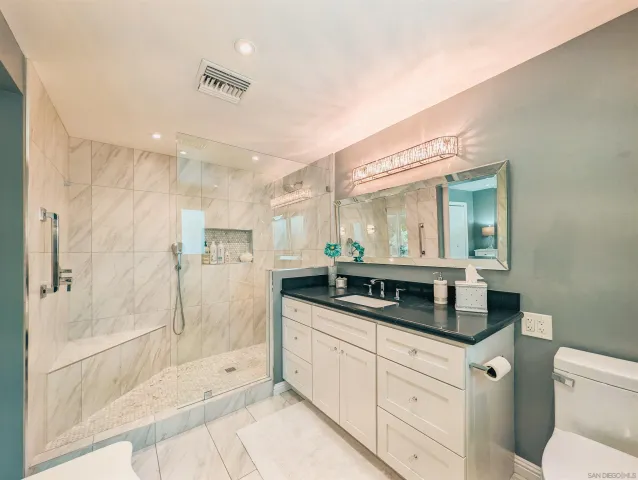 a spacious bathroom with a granite countertop sink a toilet and a mirror