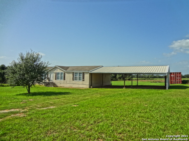 a view of a house with a big yard and large trees
