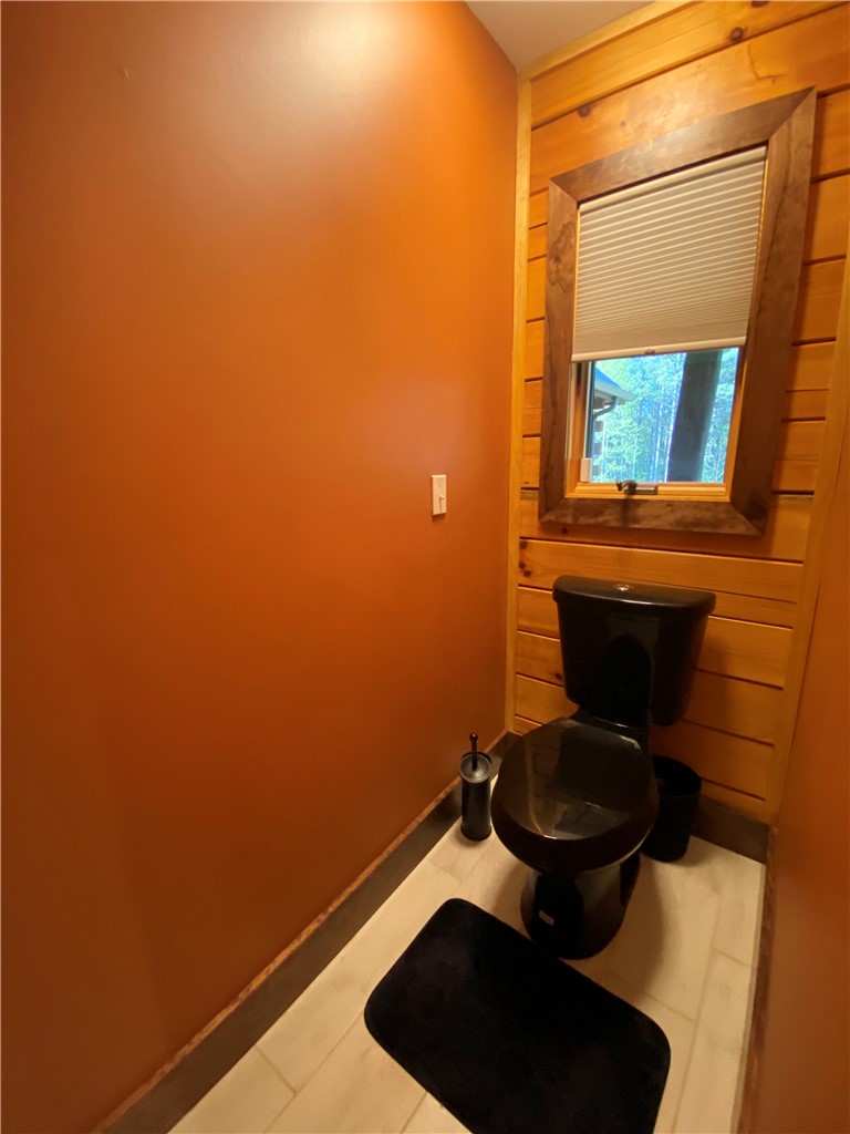 128 McAlister Road West Union, SC 29696 - Photo 16 of 40 A quaint powder room features rustic wooden paneling and a modern black toilet.