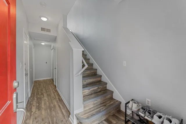 a view of a hallway with wooden floor and staircase