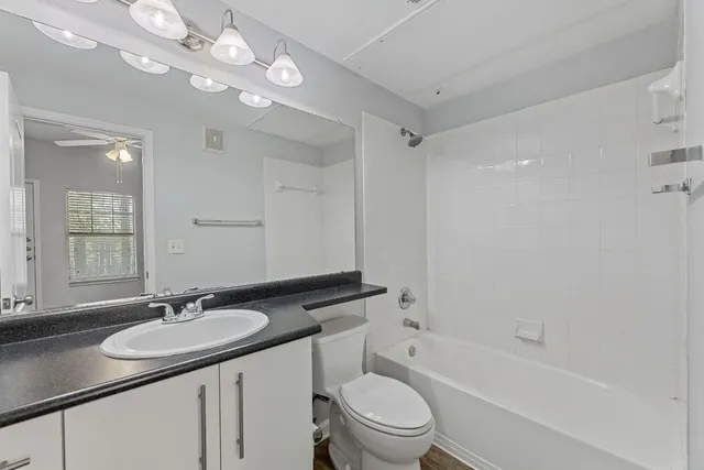 a bathroom with a granite countertop sink a toilet a mirror and shower