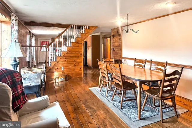 a kitchen with granite countertop a refrigerator a sink dishwasher a stove and a dining table with wooden floor